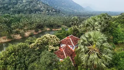 an aerial view of a house with a river and trees at Seethavanam Farmstay at Forest Edge in Kollengode