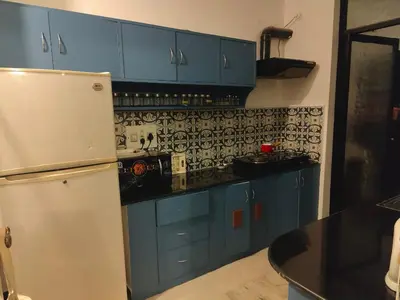 a kitchen with blue cabinets and a white refrigerator at Thambaratty in Mysore