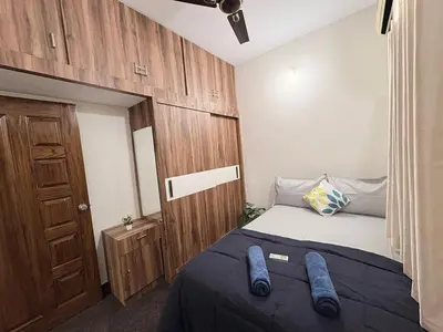 a small bedroom with a bed and a wooden door at Kamadhenu Homestay, Comapact 2BHK OPP Mysore zoo, A in Mysore