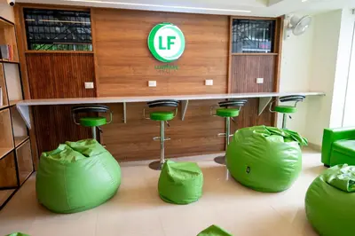 a barber shop with green chairs and a table andools at LF Easybeds in Kozhikode