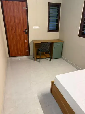 a bedroom with a desk and a wooden door and a chair at HG Tower 2 in Kunnamangalam