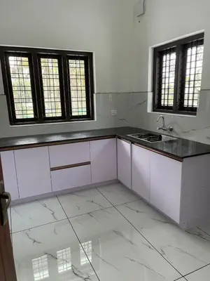 a kitchen with white cabinets and a black counter top at Wayanad Evergreen Farmhouse in Sultan Bathery