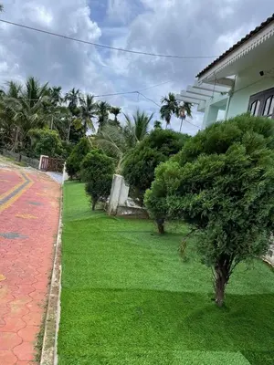 a green lawn in front of a house at Wayanad Evergreen Farmhouse in Sultan Bathery