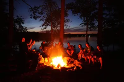 a group of people sitting around a camp fire at Chembani Holidays and Resorts Kanthalloor in Kanthalloor