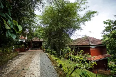 a walkway leading to a house in a garden at The Crescent Wayanad Heritage Pool Resort in Sultan Bathery