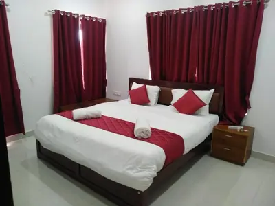 a bedroom with a large bed with red curtains at White house in Ooty