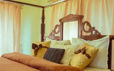 a bed with white pillows and a wooden head board at Willostays Cloudhill ooty in Ooty