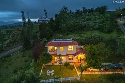 a house on a hill with its lights on at EKOSTAY - Villa Eve in Ooty