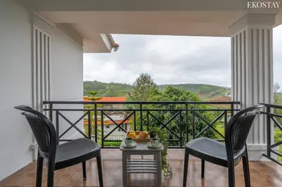 a balcony with two chairs and a table with a view at EKOSTAY - Villa Eve in Ooty