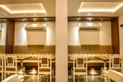 a restaurant with a long table and white chairs at Bhasuri Inn Guruvayoor in Guruvāyūr