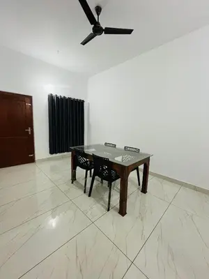 a table and chairs in a room with a ceiling fan at CT HOMESTAY, Omassery in Tāzhekkod
