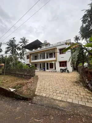 a white house with a driveway in front of it at CT HOMESTAY, Omassery in Tāzhekkod
