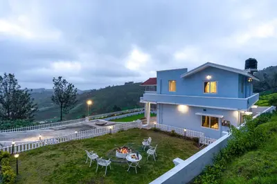 a blue house with a table and chairs at EKOSTAY - Garden Grove Villa in Ooty