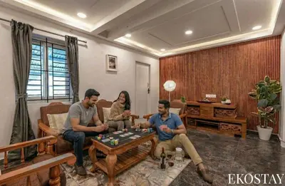 a group of people sitting in a living room playing chess at EKOSTAY - Garden Grove Villa in Ooty