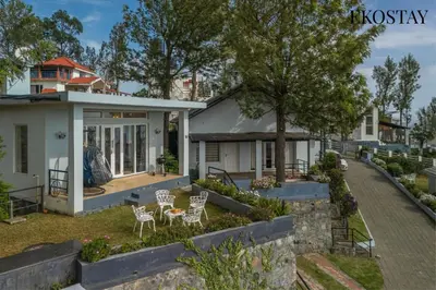 a house with chairs and a table in a yard at EKOSTAY - Skyfall Mist Villa in Ooty