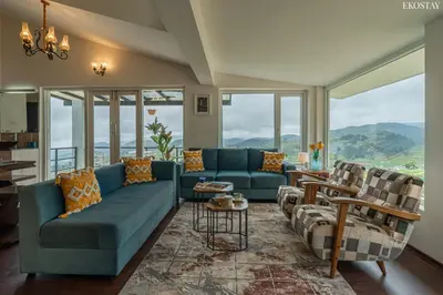 a living room with blue couches and windows at EKOSTAY - Skyfall Elysium Villa in Ooty