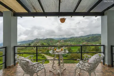 a balcony with a table and chairs and a view at EKOSTAY - Skyfall Elysium Villa in Ooty