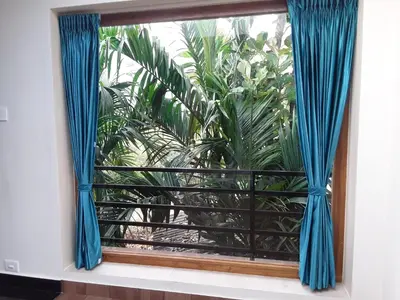 a window with blue curtains in a room with plants at SriMahi Farmhouse in Agali