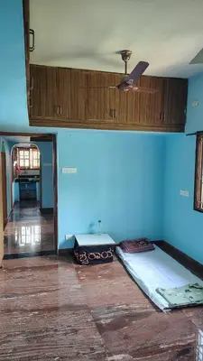 a room with a blue wall with two beds at Pine Stay in Alāndurai