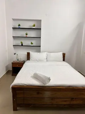 a bedroom with a large bed with a wooden frame at Shivvs Leisure Rooms & Villa Ooty in Ooty