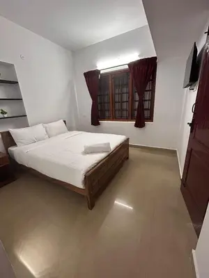 a bedroom with a bed and a window at Shivvs Leisure Rooms & Villa Ooty in Ooty