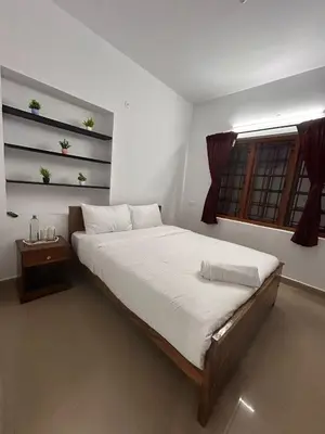 a bedroom with a large bed and a window at Shivvs Leisure Rooms & Villa Ooty in Ooty