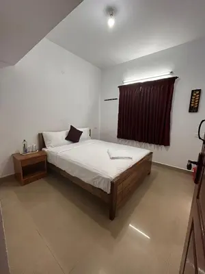 a bedroom with a large bed and a window at Shivvs Leisure Rooms & Villa Ooty in Ooty
