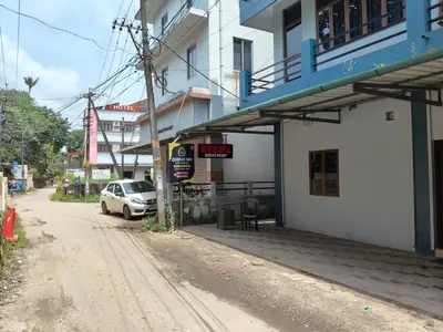 a white car parked on a street next to a building at Queens INN in Kodungallūr