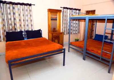 a bedroom with two beds with orange sheets and blue posts at JJ Homes in Ooty