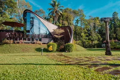 a building with a light pole in the grass at Madilina Cottage in Parūr