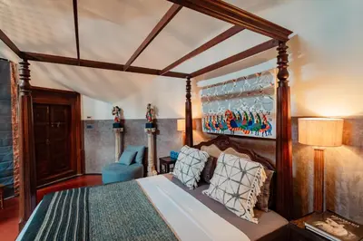 a bedroom with a canopy bed with a blue chair at Madilina Cottage in Parūr