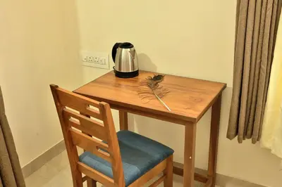 a wooden table with a tea kettle and a chair at Prithvi Nila Heavens 3 BHK Homestay Ground Floor in Guruvāyūr