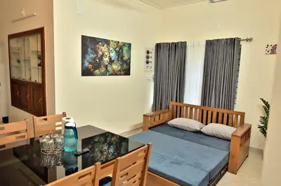 a bedroom with a bed and a table and a painting at Prithvi Nila Heavens 3 BHK Homestay Ground Floor in Guruvāyūr