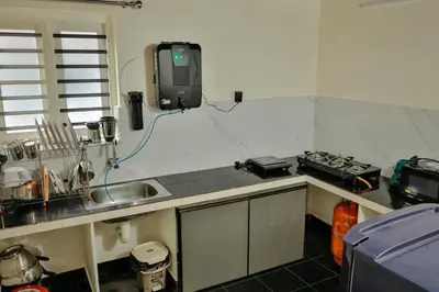 a kitchen with a sink and a tv on the wall at Akasha Nila Heavens 2 BHK Homestay - Top floor in Guruvāyūr