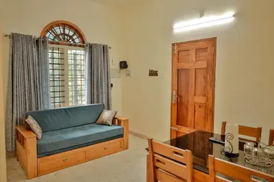 a living room with a blue couch and a wooden door at Akasha Nila Heavens 2 BHK Homestay - Top floor in Guruvāyūr