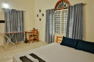a bedroom with a bed and a desk and a window at Akasha Nila Heavens 2 BHK Homestay - Top floor in Guruvāyūr