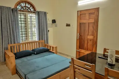 a bedroom with a bed with a desk and a door at Akasha Nila Heavens 2 BHK Homestay - Top floor in Guruvāyūr