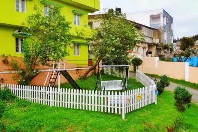 a white picket fence in a yard with a playground at Winterfell Park in Ooty
