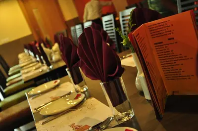 a table with two vases filled with red utensils at Hotel Atrium in Erode