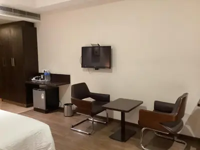 a hotel room with a table and chairs and a tv on the wall at Hotel Atrium in Erode
