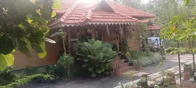 a house with a bunch of plants in front of it at Puthooram Veedu in Chakkarakkal