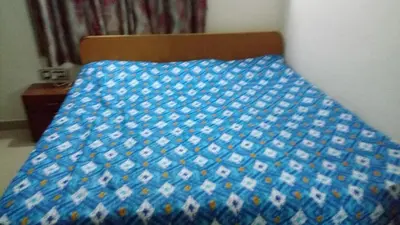 a bed with a blue comforter on top of it at Puthooram Veedu in Chakkarakkal