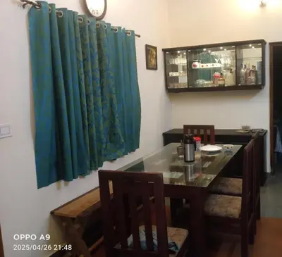 a dining room with a table and a blue curtain at Puthooram Veedu in Chakkarakkal
