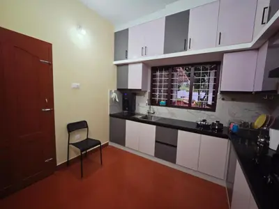 a kitchen with white cabinets and a chair in a room at Tranquil Nest Villa - 4BHK Villa - Entire Villa stay in Wayanad in Kalpetta