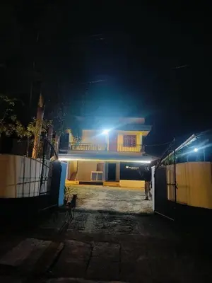 a man standing in front of a house at night at Clap House Home in Guruvāyūr