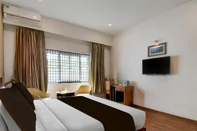 a hotel room with a bed and a flat screen tv at Super Townhouse Oak Sri Mahadeshwara Convention Centre Formerly Shri Aprameya Resort in Mysore