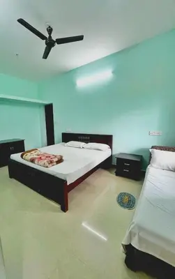 a bedroom with two beds and a ceiling fan at The Wild House in Kotagiri