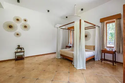 a bedroom with a canopy bed and a tiled floor at Punya Farms - Luxury 5BR near Isha Yoga in Alāndurai