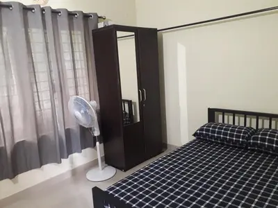 a bedroom with a bed and a fan and a window at Peaceful Vacation Home Near the City in Cochin
