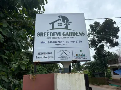 a sign for a backyard garden on a street at Sreedevi Gardens in Irikkūr